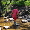 Alex hops across a creek