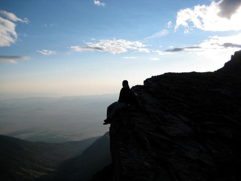 A daring hiker sits on the NE edge of the summit. This part of the summit need not be climbed and is easily avoidable for those afraid of heights.