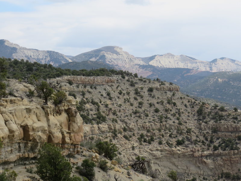 Looking back at the trail clinging to the slope and beyond to the Bookcliff Mountains