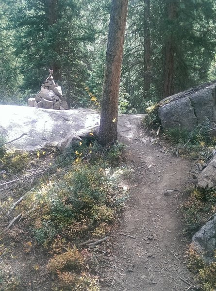 A huge cairn marks the top of the steep stone stairs up from the creek