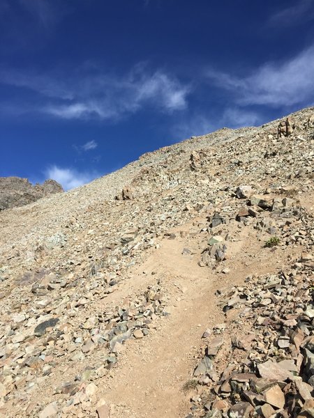 After rounding the ridge, continue on loose trail before reaching the rocky, scrambly area.