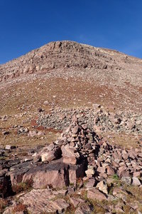 The large rock cairn at Gunsight Pass.  In the background is the cliff band that runs beneath West Gunsight Peak (Dome Peak).