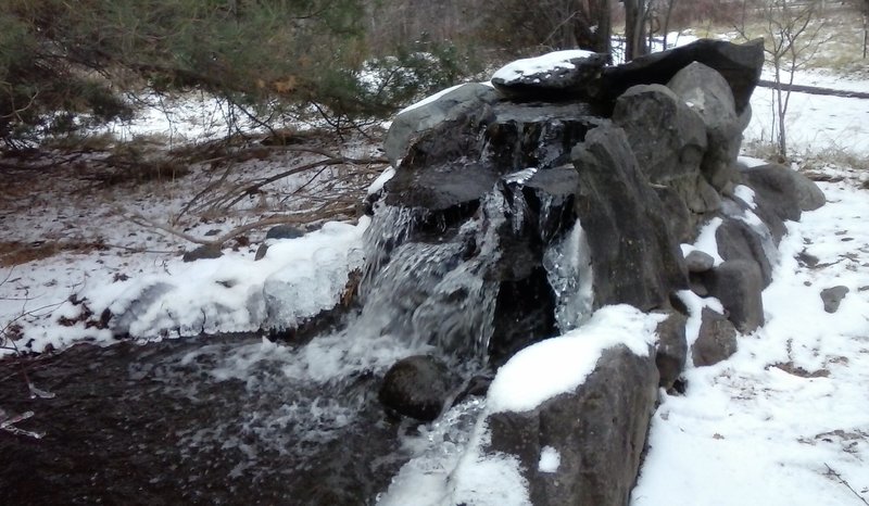 The small waterfall adorned with snow and ice.