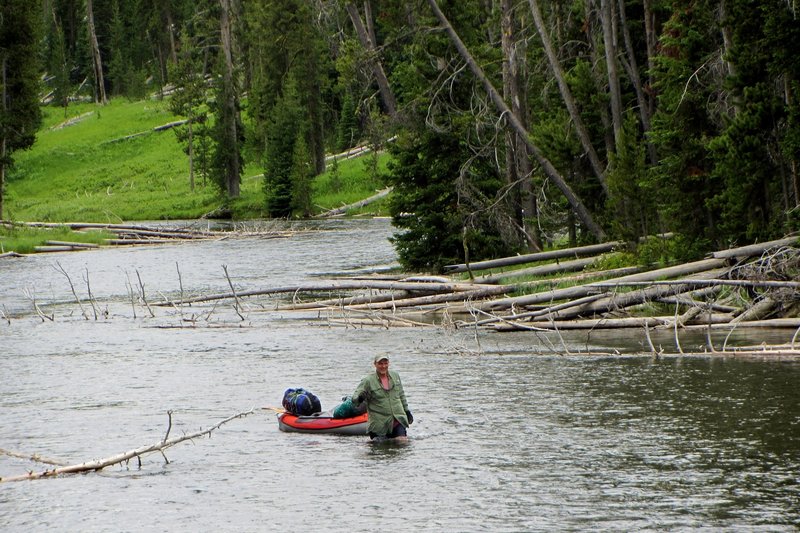 A kayaker walks his kayak up the Lewis River Channel through a section that flows too fast to paddle against.