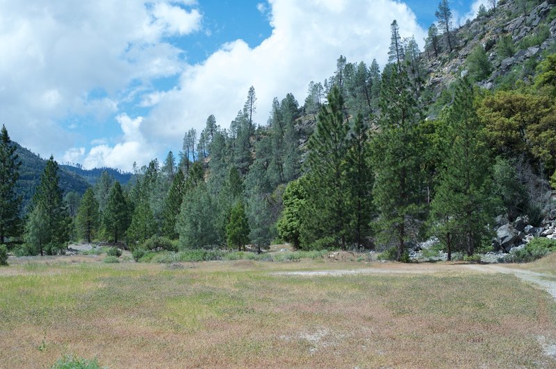 The trail as it enters an open field. Flowers bloom in the spring, and dam workers and rangers can be find resting here.