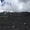 A couple of hikers on the "trail" with Mt St. Helens in the background obscured by clouds.