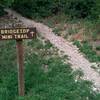 Trailhead marker pointing where the trail begins on the south side of the bridge.