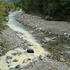 Red Rock Creek, milky with silt, joins the clear Bauerman Creek.