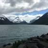 Snow-capped mountains see the sun peek through the clouds in the middle of summer on the Kenai Peninsula.