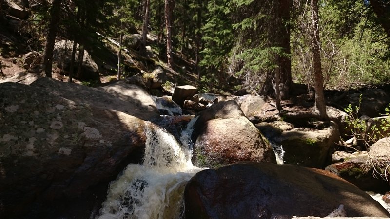 Multiple small, cascading waterfalls flow along Rough And Tumbling Creek.