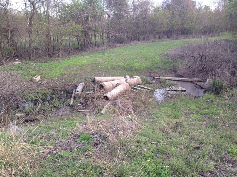 A pile of debris offers access across the wet ditch to the north end of the Addicks-Fairbanks Trail.
