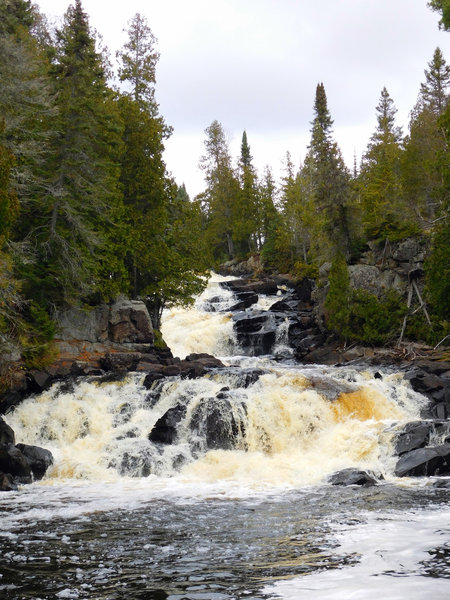 Raging water rushes through a volcanic canyon.