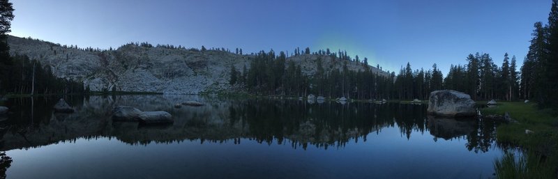 The lake is still just as the sun climbs over the mountain in the background.