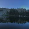 The lake is still just as the sun climbs over the mountain in the background.