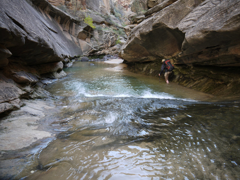 A hiker edges through the narrows of Lower Death Hollow.