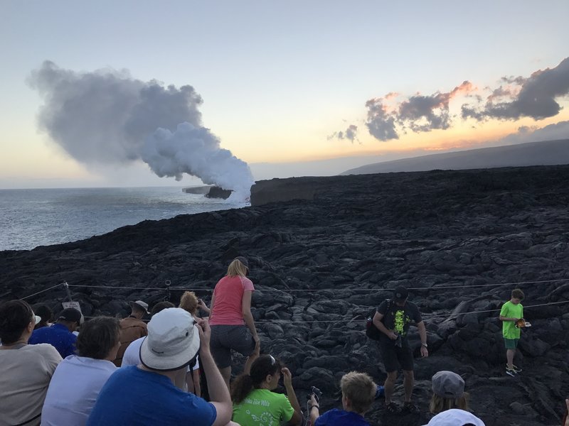 A mass of people watch the sunset at the Kamokuna ocean lava viewing area.