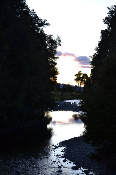 The sun sets over the beginning of the trail on the swing bridge.