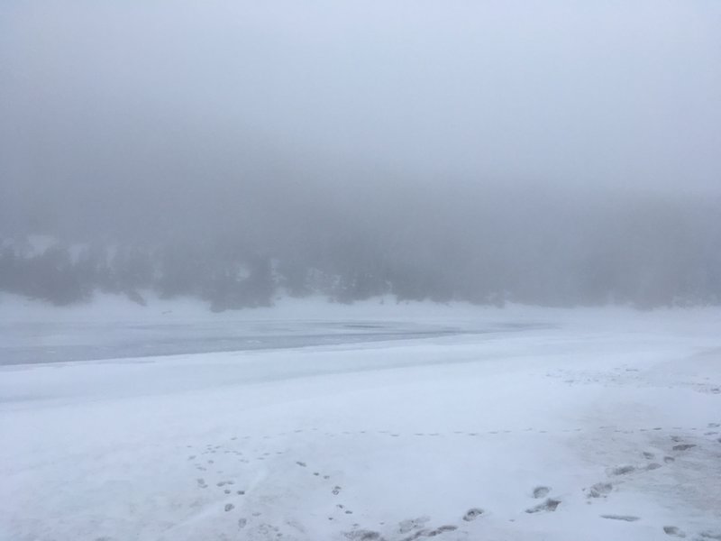 Frozen Kinsman Pond can be seen through the fog.