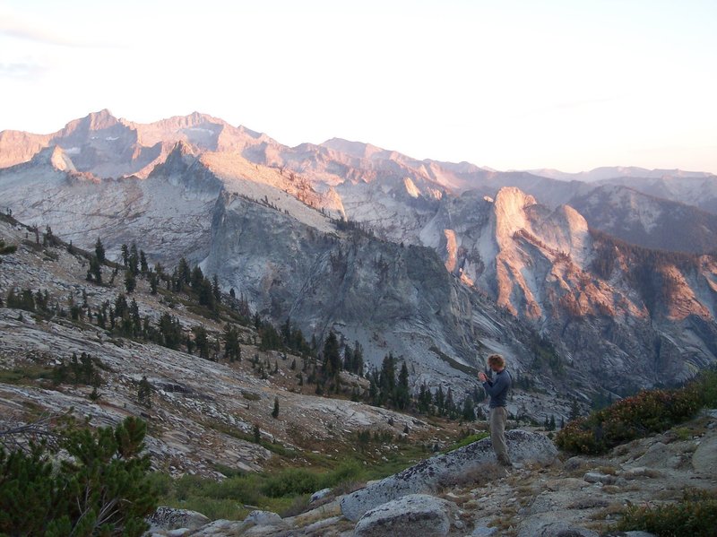 A hiker photographs the sunset on the ridge.