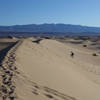 A photographer ascends a dune at Mesquite Sand Dunes.