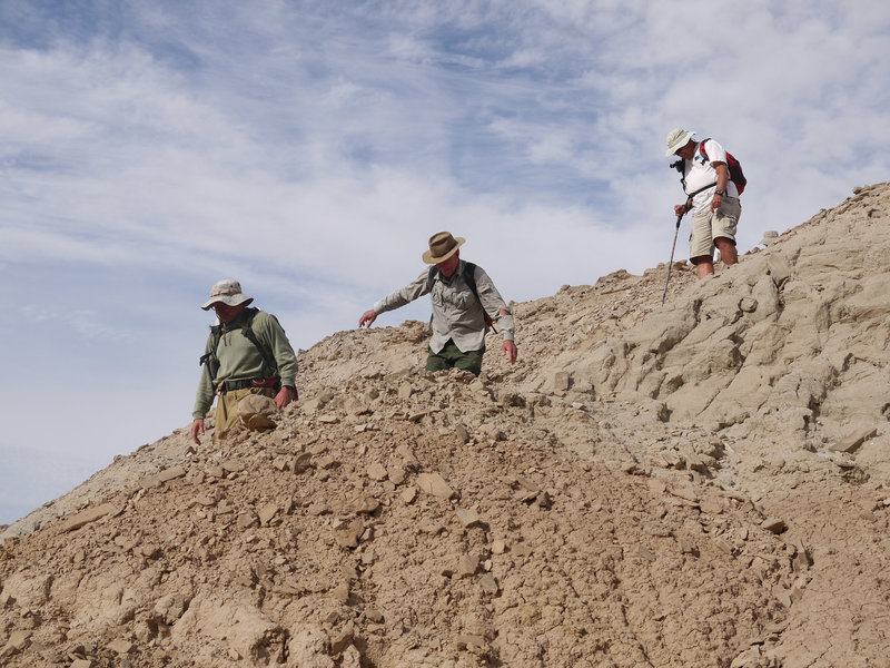 Three Monday Maniacs descend a mud hill.