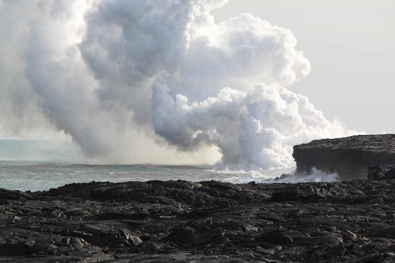 Steam billows from active lava flows plunging into the sea.