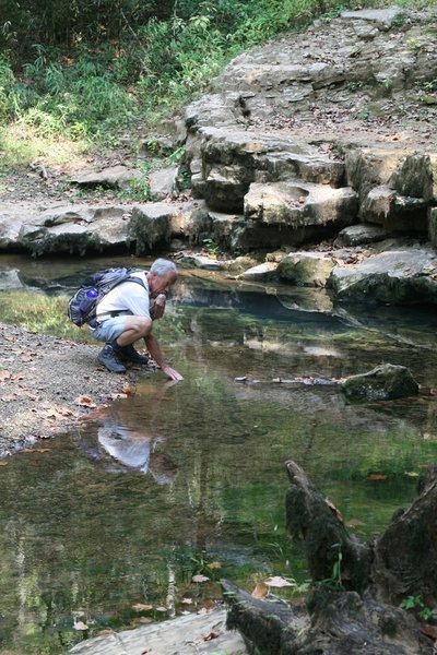 A visitor feels the cool water flowing out of Echo River Springs. Photo credit: NPS Photo.