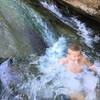 A child slides into a pool in the river next to Cross Camp.