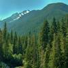 The north shoulder of Tricouni Peak looms ahead, with Thunder Creek far below, as Thunder Creek Trail nears McAllister Camp