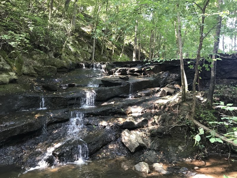 You can scramble right up to the base of the small waterfall in the spillway off the Wild Azalea Trail.