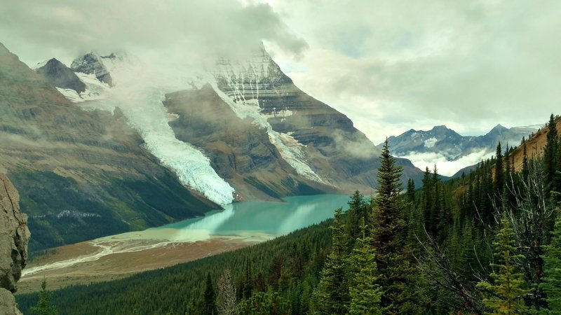 Mt. Robson in the clouds, with Berg Lake at its foot, and the mountains across the Robson River Valley in the distance, looking southwest from high on Mumm Basin Route