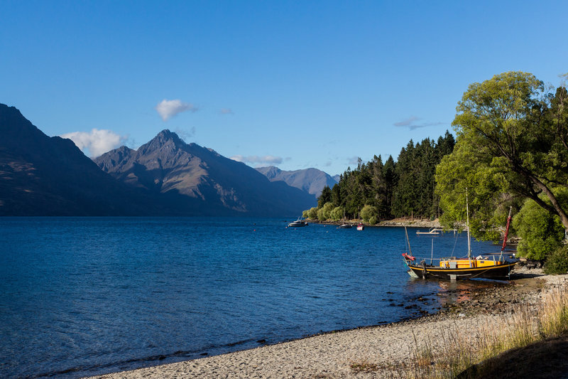 Small boats are anchored at the shore of Lake Wakatipu