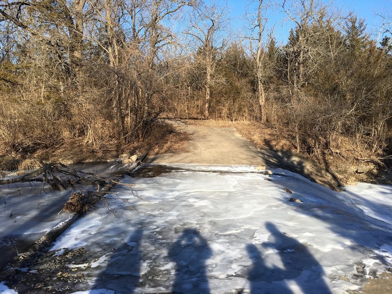 A frozen, paved creek crossing.