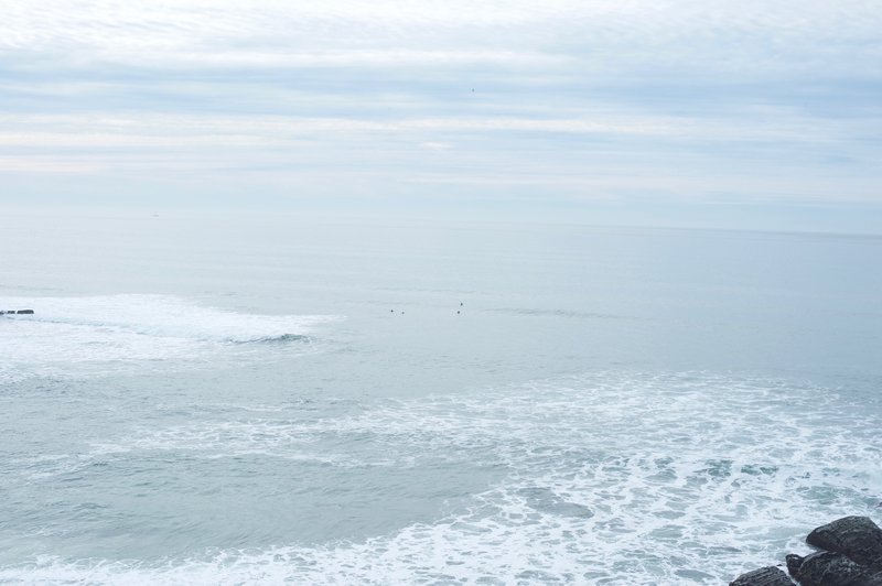 Surfers wait for waves in the ocean below.