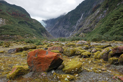 Colorful rocks in Franz Josef Glacier Valley with the glacier in the distance