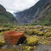 Colorful rocks in Franz Josef Glacier Valley with the glacier in the distance