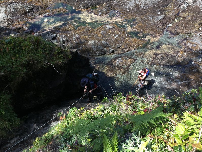 A couple of hikers climbing up the rope.