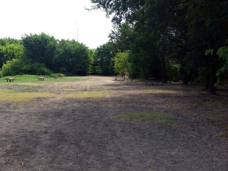 Benches to the left by the pond, and picnic tables to the right, on the trail leg shared by Pond & River Loops