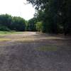 Benches to the left by the pond, and picnic tables to the right, on the trail leg shared by Pond & River Loops