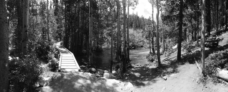 Small off trail wood bench overlooks a wide path of moving water, perfect spot for a lunch break.