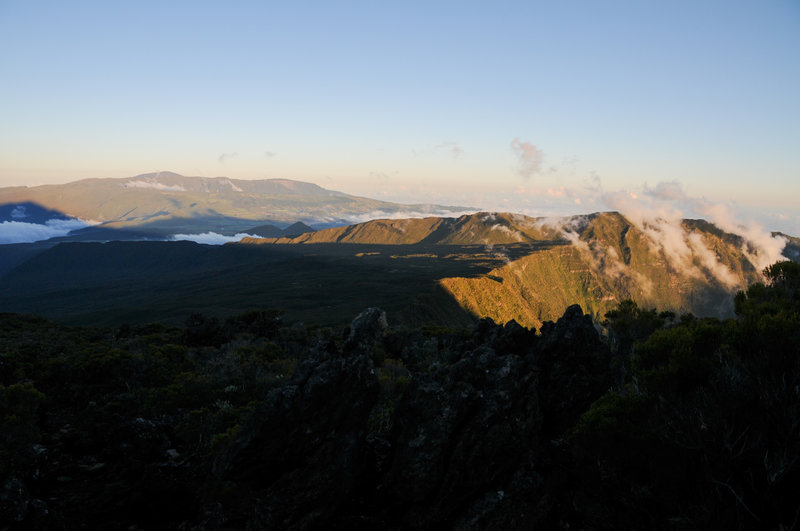 Clouds climb out of Cirque de Cilaos at dusk. Piton de la Fournaise is in the distance.