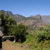A wooden statue of a hiker can be found near a picnic table at the southern base of Piton Cabris. In the distance is Grand Benare.
