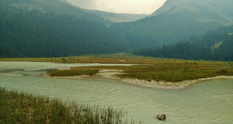 A small glacial lake in the mountain meadows, is passed by Coleman Glacier Trail. This lake is fed by the glacial creek flowing down the gap in the center between the 2 mountains. A glacier behind the mountain on the right is the creek source.