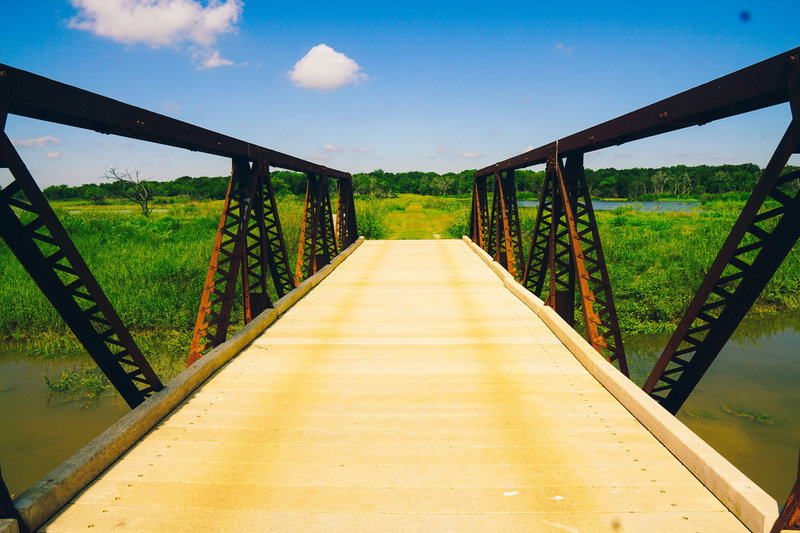 A small truss bridge provides egress over a large seasonal overflow creek.