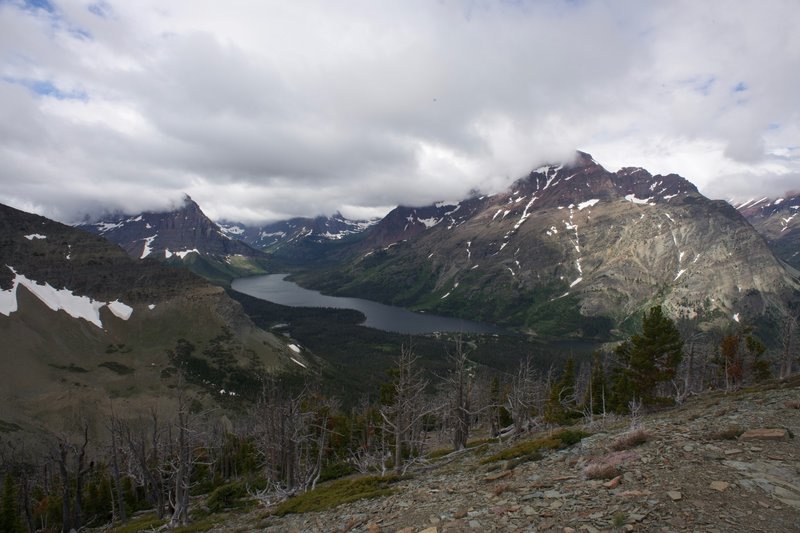 Two Medicine Lake sits far below the trail. Even though it was a cloudy day, the rays of sun lit up the mountains.