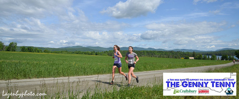 Two racers run along Kings Farm Rd, with Little Hosmer Lake and the Lowell Mountain Ridge visible in the background