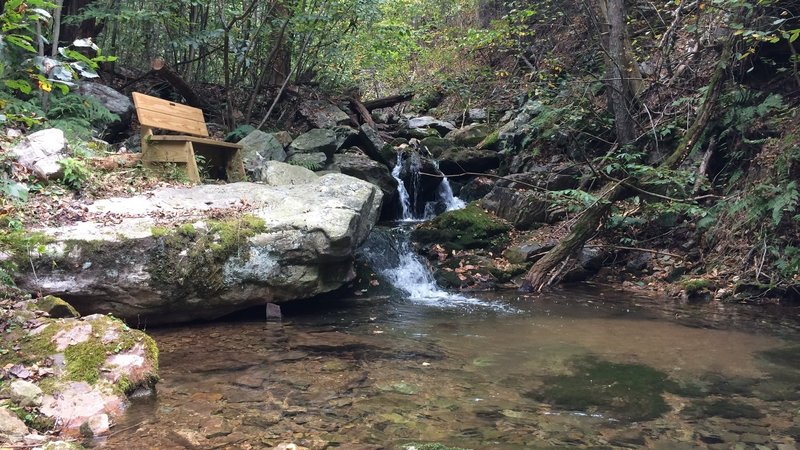 Bench at water cascade along creek