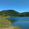 Guadalupe Reservoir in April. Orange monkey flowers bloom on the bush at the left.