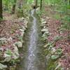 Water from recent rainstorms is diverted under the trail through troughs like this.