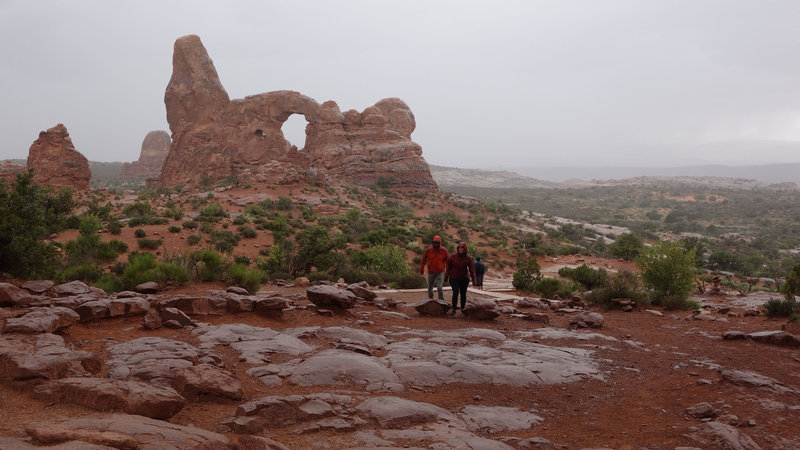 Two hikers approach the North Window Arch.